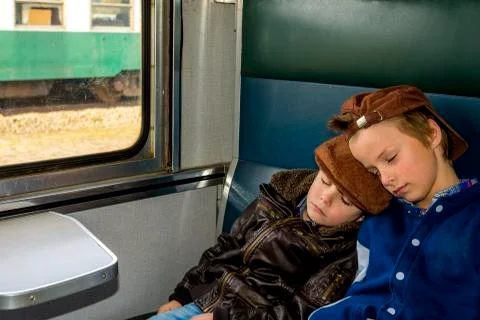 Two boys sleeping in a train during their travel Stock Photos