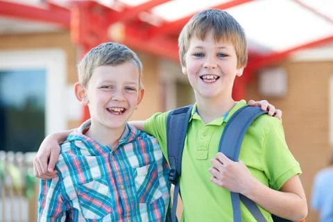 Two Boys Standing Outside School With Book Bags Stock Photos