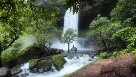 Two Boys Standing on a Rock with Waterfall Cascading from Mountain Stock Footage 285075192
