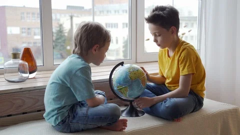 Two boys studying the geography of the earth with a globe. Stockbeeldmateriaal 105090666