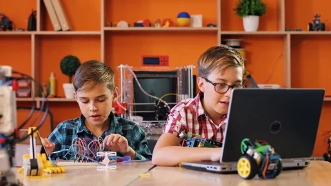 Two boys using assembling robotic machines and cheking how to do it on the Stock Footage 82492457
