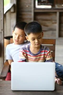 Two Boys Using Laptop in Rustic Setting Stock Photos