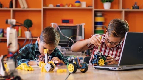 Two boys using screwdrivers to assemble robotic machines and watching how to do Stock Footage 82489311