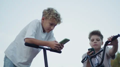 Two Boys Using Smartphones in Skate Park Low Angle Shot Stock Footage 346156905