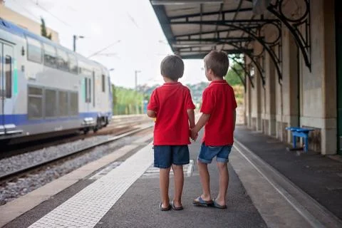 Two boys, watching a train leaving a station Stock Photos