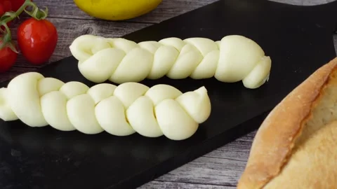 Two braided cheese pieces sit next to a loaf of fresh bread Stock Footage 309904515