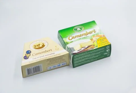 Two brands of Camembert soft-ripened cheese boxes closeup on white. Stock Photos