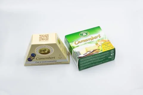 Two brands of Camembert soft-ripened cheese boxes closeup on white. Stock Photos