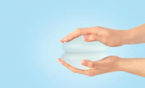 Two breast implants in hands on blue background , copy space. Stock Photos