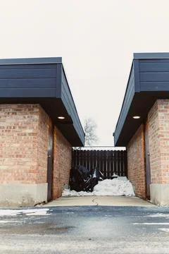 Two brick buildings stand on either side of a snowy path. Between them, a bla Stock Photos