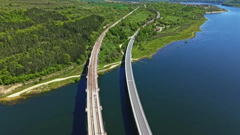 Two bridges cross over a river with green hills and trees on either side during Vidéo 342483986