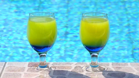 Two bright beautiful yellow-blue cocktails stand close-up on side pool Vidéo 132646426