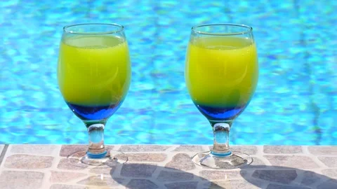 Two bright beautiful yellow-blue cocktails stand close-up on side pool 库存影片 132649655
