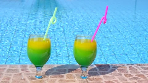 Two bright beautiful yellow-green-orange cocktails with straws glasses stand Vidéo 130532246