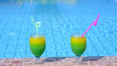 Two bright beautiful yellow-green-orange cocktails with straws glasses stand Vidéo 130534109