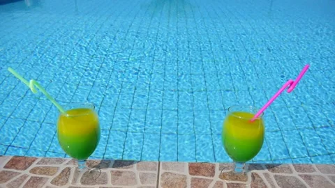 Two bright beautiful yellow-green-orange cocktails with straws glasses stand Vidéo 130573335