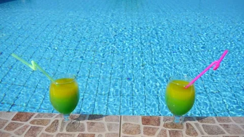 Two bright beautiful yellow-green-orange cocktails with straws glasses stand Stock Footage 130574695