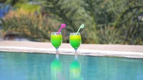 Two bright beautiful yellow-green-orange cocktails with tubes in glasses stand Vidéo 130575403