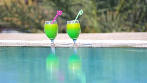 Two bright beautiful yellow-green-orange cocktails with tubes in glasses stand Stock Footage 130576411