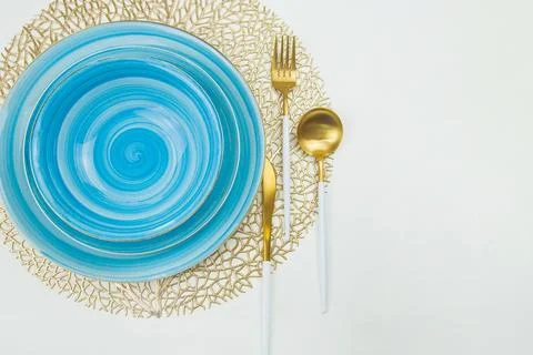 Two bright blue plates, serving and deep, stand on golden napkins, serving Stock Photos