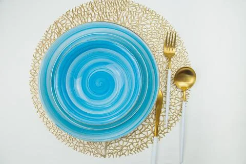 Two bright blue plates, serving and deep, stand on golden napkins, serving Stock Photos