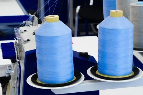 Two bright blue thread spools rest on sewing machine. Spools have yellow tops Stock Photos