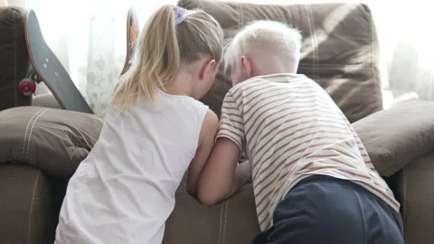 Two bright children, a boy and a girl, enthusiastically use a mobile phone at Stock Footage 207994596