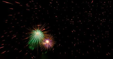 Two bright multicolored flashes of fireworks flying through sparks against black Stock Photos