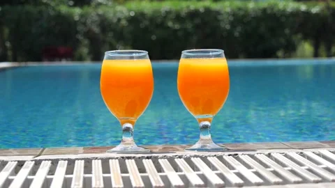 Two bright orange glasses close up with cocktail or juice with ice stand Stock Footage 138873186