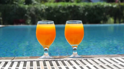 Two bright orange glasses close up with cocktail or juice with ice stand Stock Footage 138873227