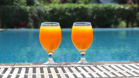 Two bright orange glasses close up with cocktail or juice with ice stand edge Stock Footage 138873343