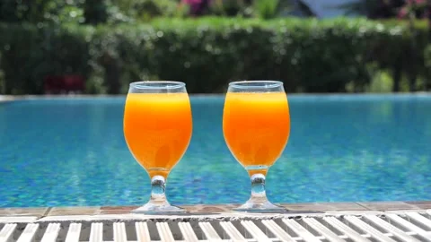 Two bright orange glasses close up with cocktail or juice with ice stand edge Stock Footage 138873469