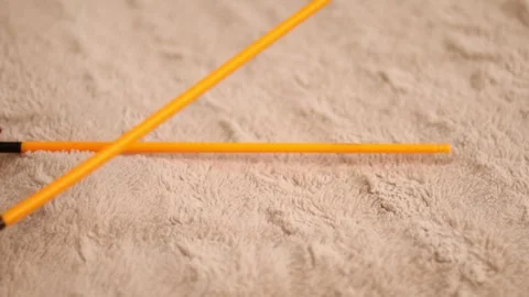 Two bright orange plastic sticks are tapped together, producing a steady rhythm Stock Footage 320353609