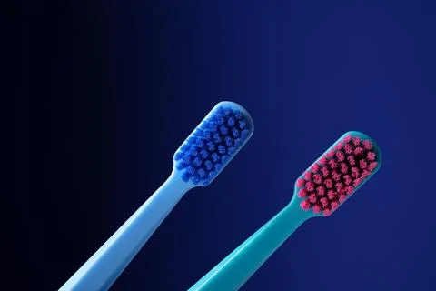 Two bright plastic toothbrushes on a dark blue background. Stock Photos