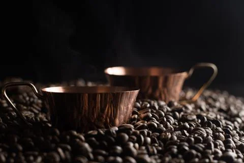 Two bronze cup full of coffee on the grains pile. Italian traditional morning Stock Photos