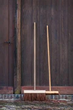 Two brooms in front of an old barn Stock Photos