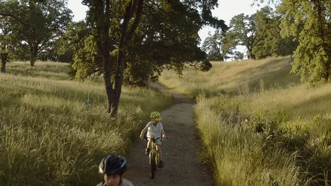 Two Brothers biking together on a path moving dolly shot Stock Footage 75022224