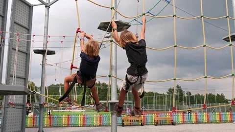 Two brothers boldly navigate obstacles in a rope park, strengthening their bond Stock Footage 250880354