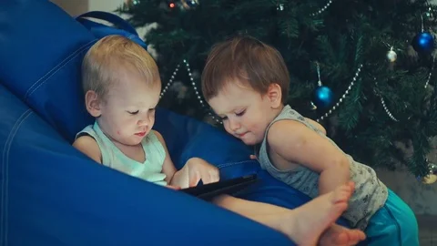 Two brothers of the boy play on a tablet on Christmas day Stock Footage 83722908