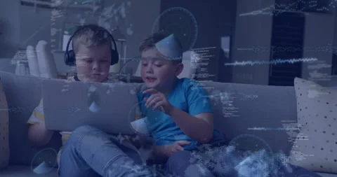 Two brothers on couch right boy leaning and tapping laptop teaching code with Stock Footage 331634384