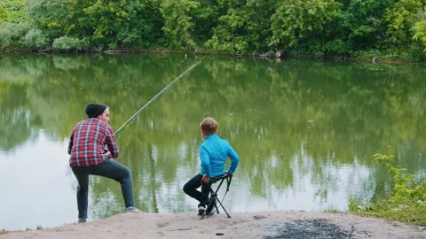 Two brothers on fishing - man pulling the rod and his little brother watching Stock Footage 136033132