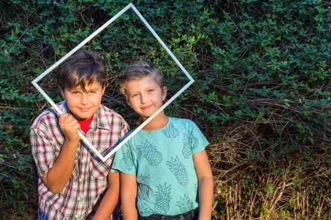Two brothers looking through frame Two cute boys - brothers looking throug... Stock-Fotos