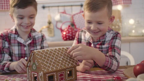 Two brothers making and decorating gingerbread house on christmas eve Stock Footage 144890734