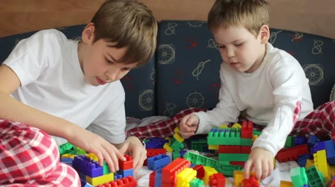 Two brothers in pajamas playing constructor on the bed Video stock 61005029