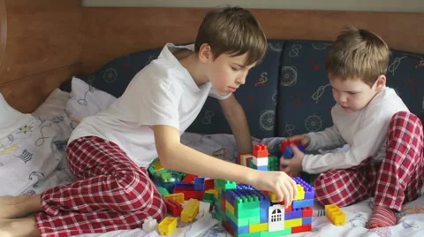 Two brothers in pajamas playing constructor on the bed Stock Footage 61583457