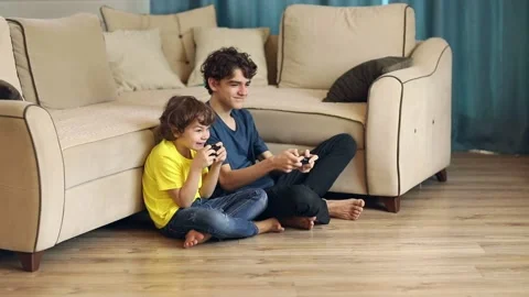 Two brothers play a game console, the older one lost, the younger one won Stock Footage 168391894