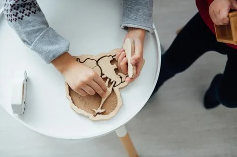 Two brothers play puzzle on the table in the children's room in the Scandinavian Stock Photos