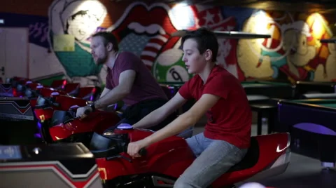 Two brothers playing arcade video racing game Stock Footage 58627259