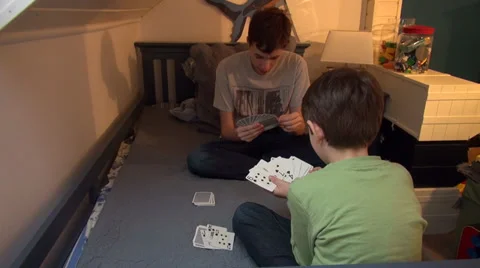 Two brothers playing cards at home, boys enjoying game, having fun Stock Footage 33797048