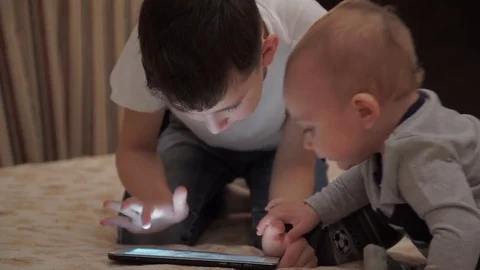 Two Brothers Playing With Digital Tablet On Sofa Video stock 70065590